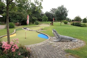 A miniature golf course with a pond, a statue, and surrounding greenery. - Holiday home in Norddeich with Wi-Fi (Norddeich)