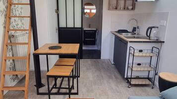 Un espace de vie compact comprenant une cuisine en mezzanine, un coin repas et un canapé.