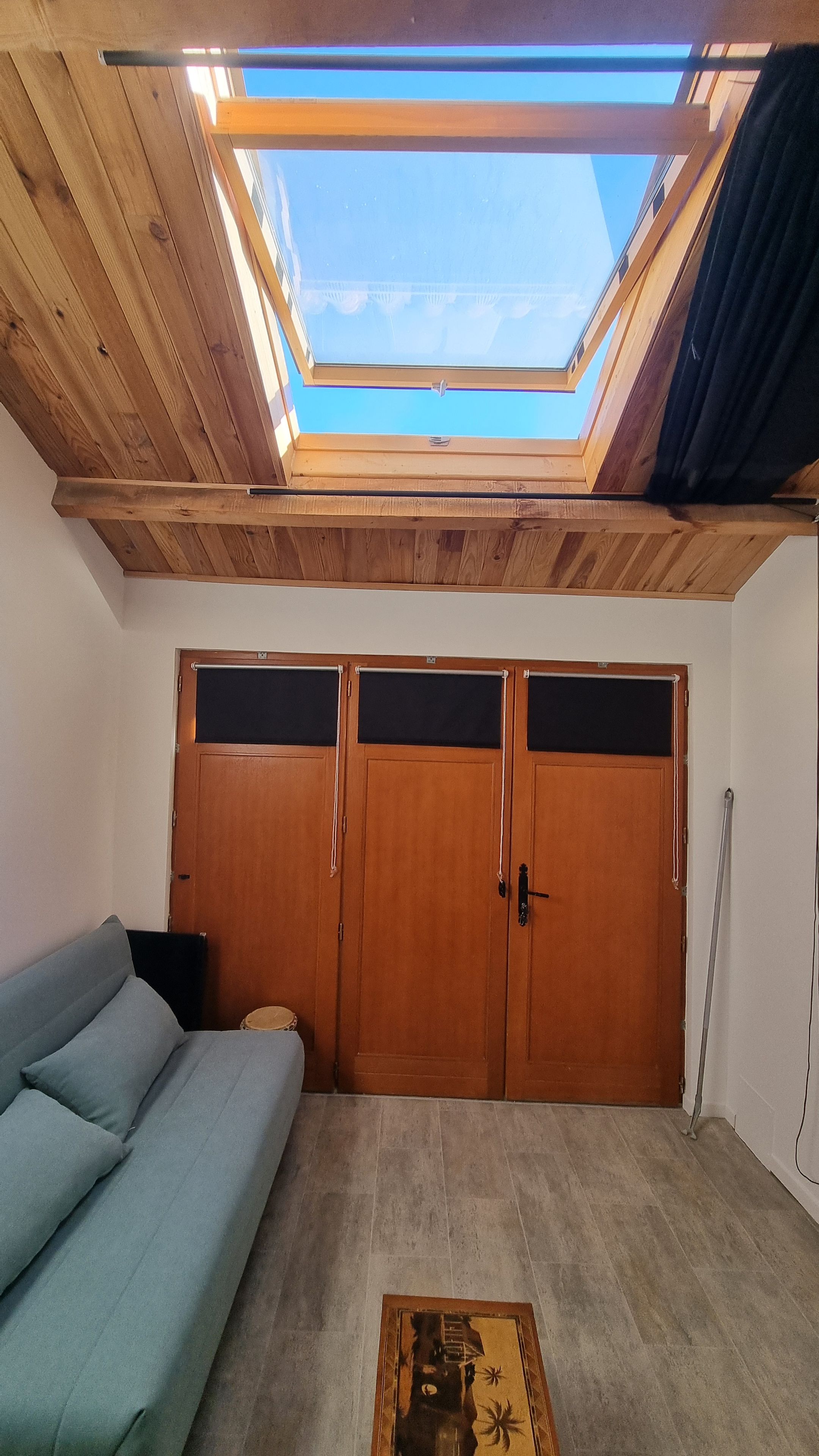 Une pièce dotée d’une lucarne, d’une armoire en bois et d’un canapé.
