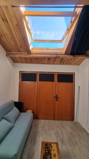 Una stanza con finestra sul tetto, un'armadio in legno e un divano.