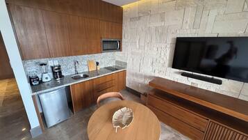 A modern kitchen with a stone wall, built-in microwave, and a flat-screen TV.