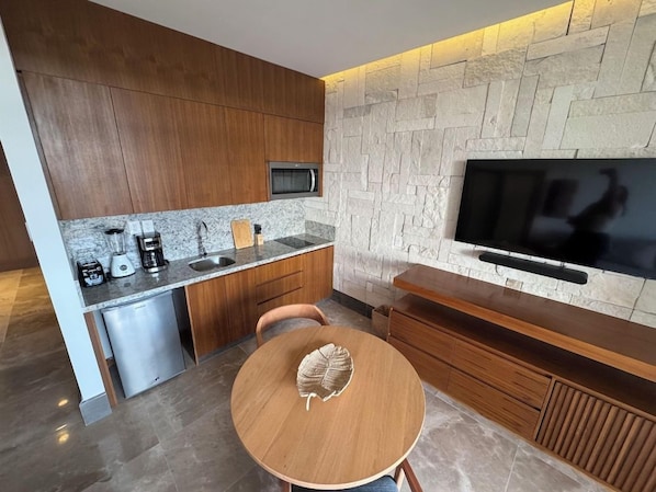 A modern kitchen with a stone wall, built-in microwave, and a flat-screen TV.