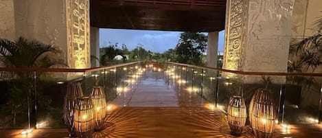 An outdoor pathway with a glass railing, leading to a covered area with a wooden roof.