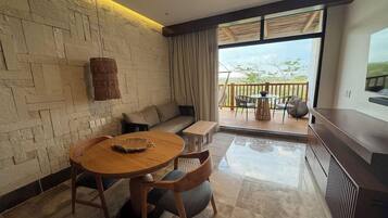 A modern living room with a stone wall, a round wooden table, a sofa, and a balcony with outdoor furniture.
