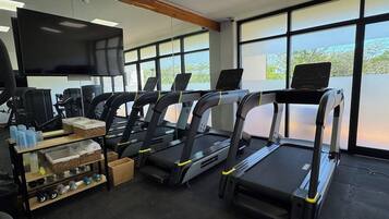 A gym with treadmills, exercise equipment, and a TV screen.