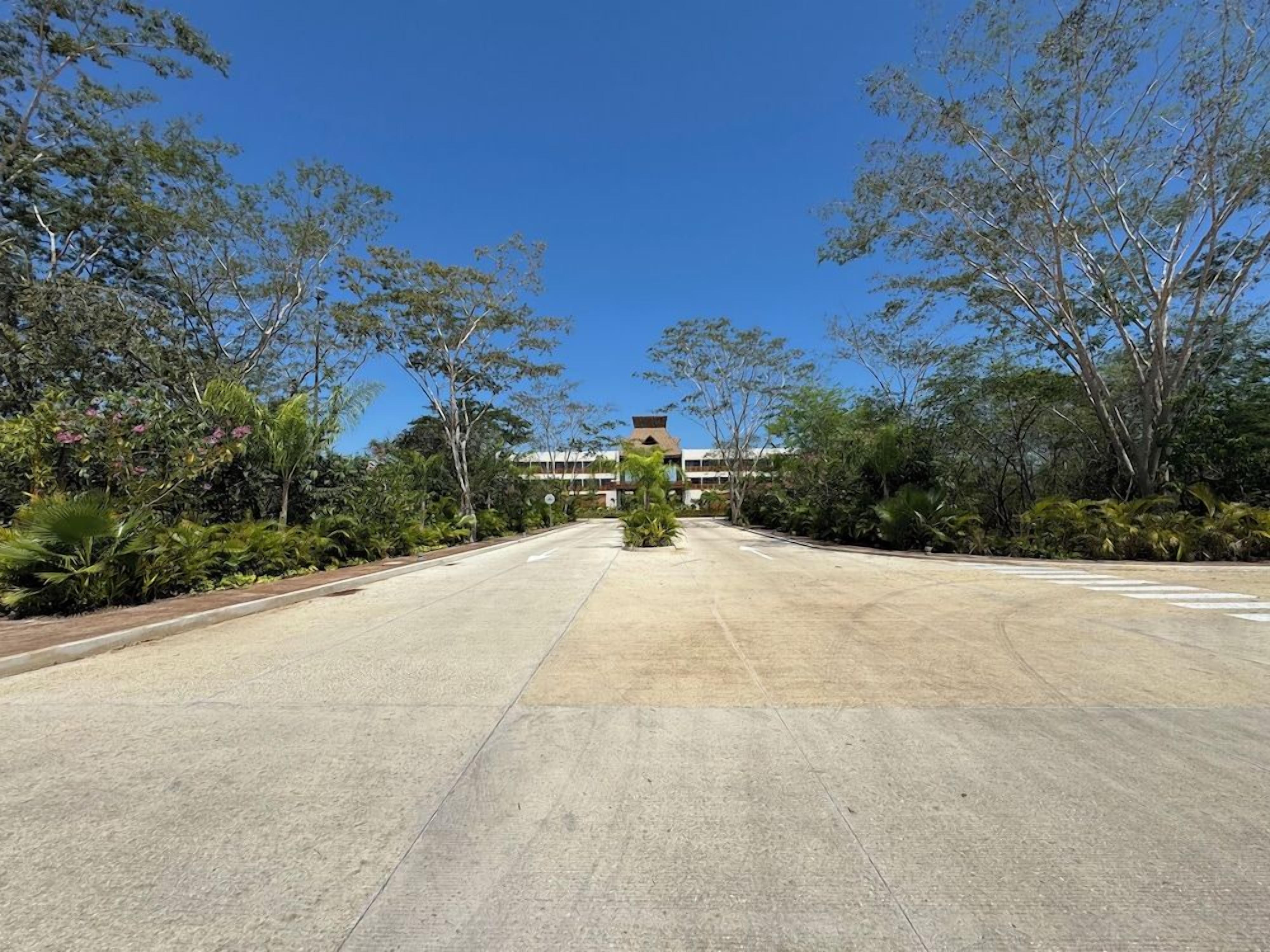 A wide, empty road leading to a building with a flat roof and multiple windows.