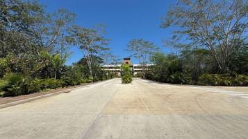 A wide, empty road leading to a building with a flat roof and multiple windows.