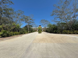 A wide, empty road leading to a building with a flat roof and multiple windows.