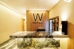 A reception desk with a marble top, a wooden wall with a 'W HOTEL' sign, and a small seating area. - Hotel W Santa Marta (Santa Marta)