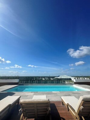 A rooftop pool with lounge chairs and a clear view of the city skyline. - Hotel Gafsacomm Tulum Aeropuerto (Mérida)