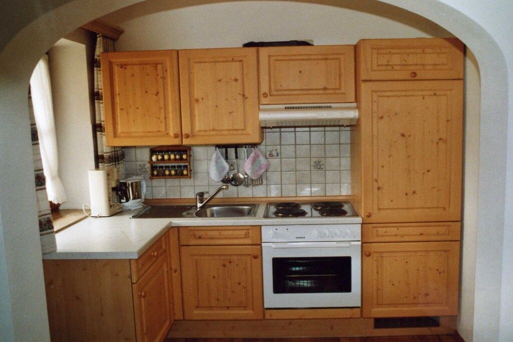 Une cuisine avec des meubles de rangement en bois, un plan de travail blanc, une cuisinière et un four.