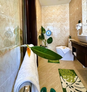 A bathroom with a marble wall, a sink, a toilet, and a shower area. - Century Hotel Da Nang (Da Nang Municipality)