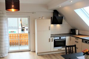 A modern kitchen with white cabinetry, a built-in oven, and a black range hood. - Holiday apartment with 2 bedrooms (Oberammergau)