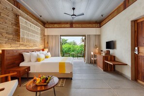 Habitación de hotel con cama, escritorio, televisión y vistas a zonas verdes.
