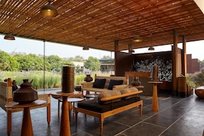 A spacious outdoor seating area with a wooden ceiling and large windows overlooking a garden. - Woods At Sasan (Mendarda)