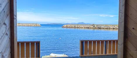 A wooden deck with a view of a calm sea and rocky breakwaters.