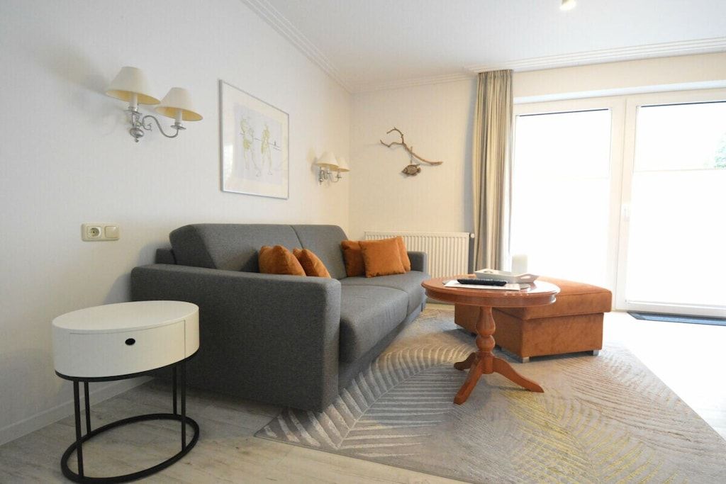 A modern living room with a grey sofa, a round side table, a small wooden coffee table, and a patterned rug.