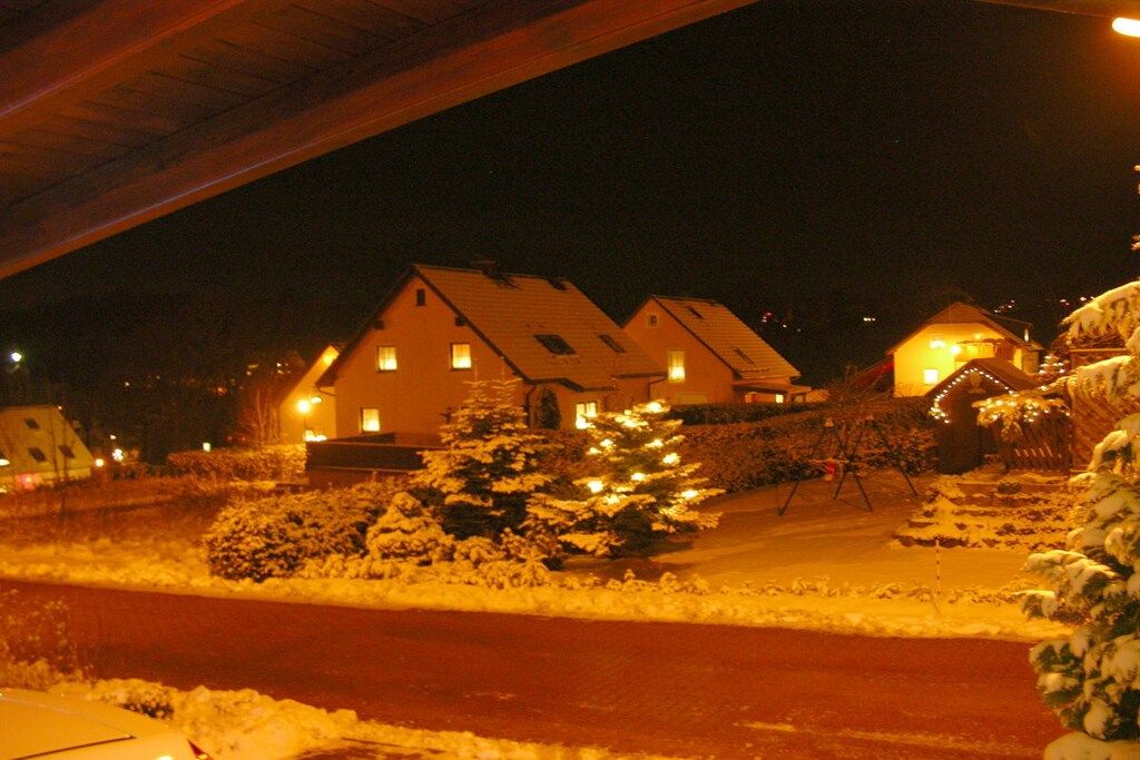 Een woongebied 's nachts, met huizen en een besneeerd landschap.
