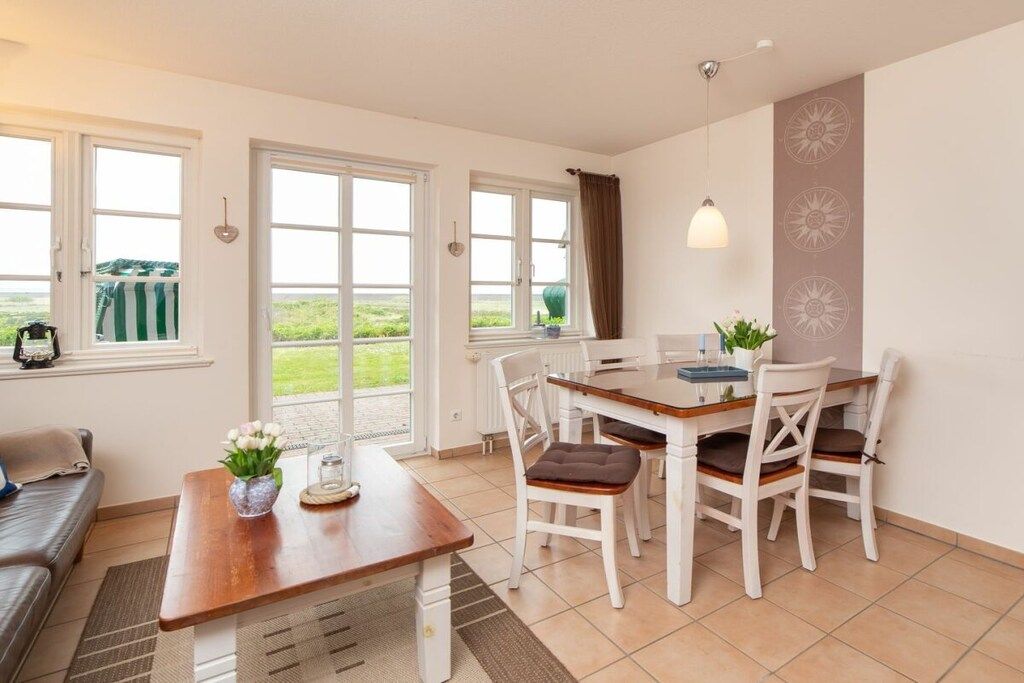 A dining area with a table and chairs, a sofa, and a view through the windows.