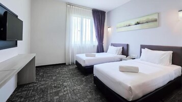 Habitación de hotel con dos camas, un televisor de pantalla plana, un escritorio y un cuadro en la pared.