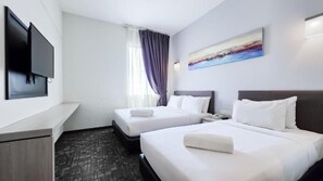 Quarto de hotel com duas camas, televisão de tela plana na parede, um quadro sobre as camas e uma janela com cortinas.