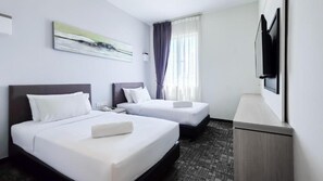 Quarto de hotel com duas camas, televisão de tela plana, um quadro na parede e uma janela com cortinas.