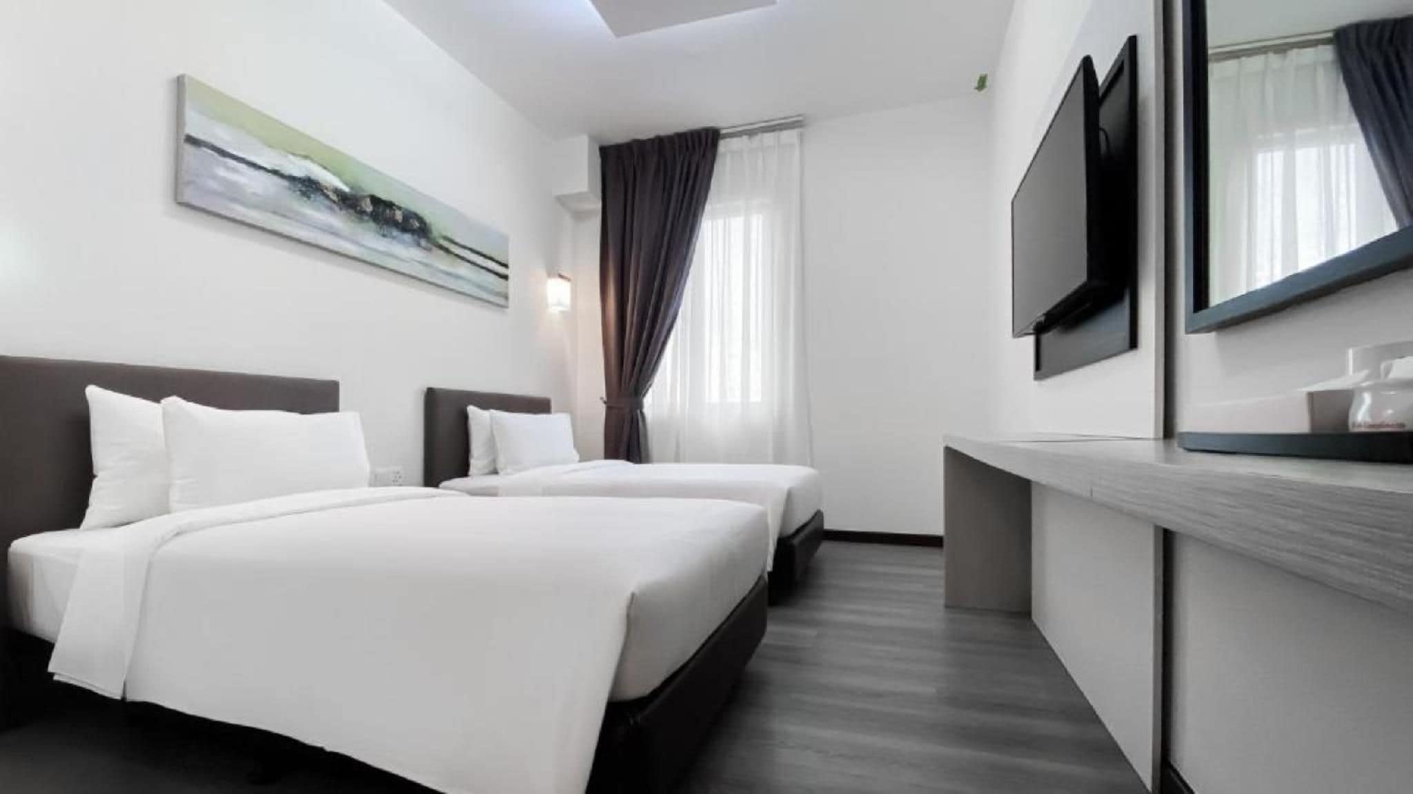 A hotel room with two beds, a flat-screen TV, a painting on the wall, and a window with curtains.