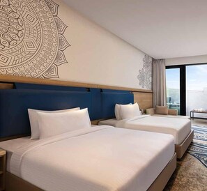 Habitación de hotel con dos camas, un mural grande en la pared y vistas a la ciudad.