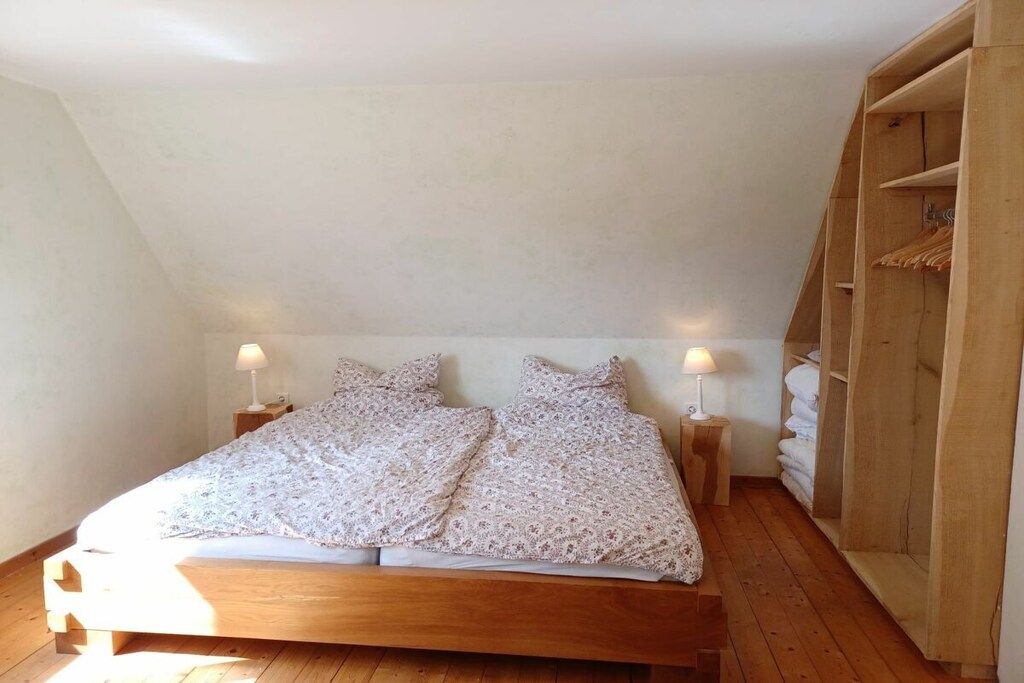 Une chambre à coucher avec un lit en bois, deux tables de chevet avec des lampes et une armoire en bois.