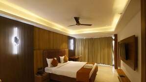 Een moderne hotelkamer met een groot bed, een plafondventilator, een flatscreen televisie en een houten accentmuur.