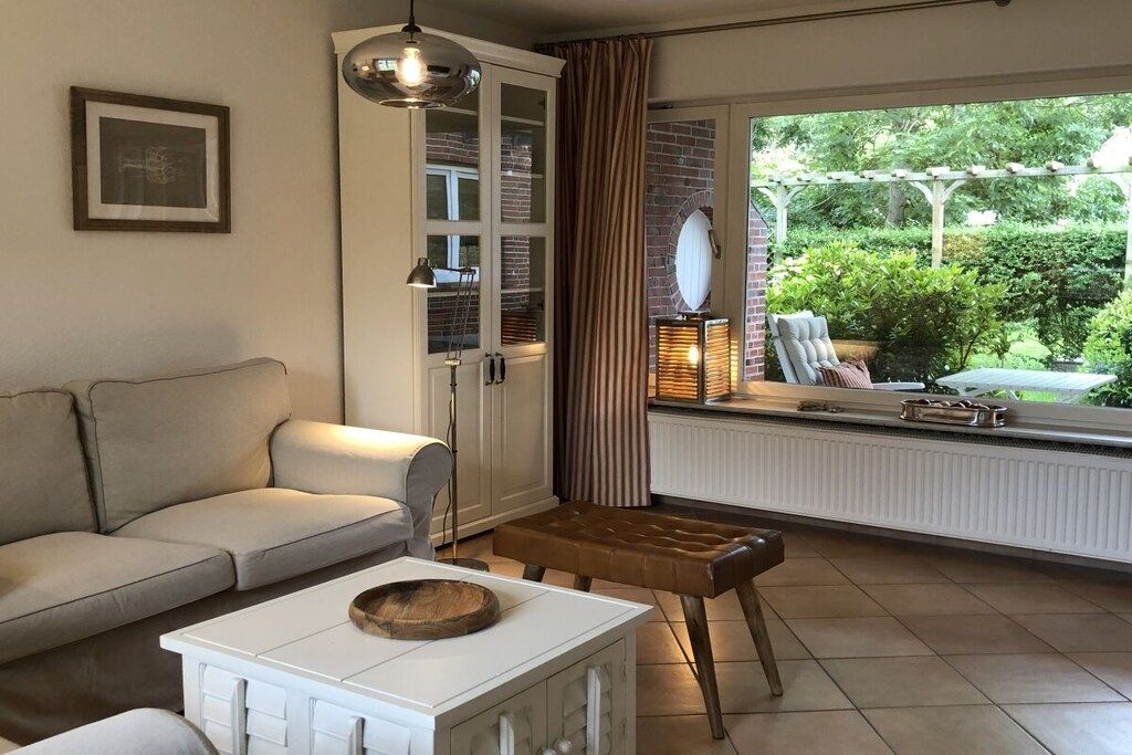 A living room with a sofa, a coffee table, a side table, a lamp, and a view of the outdoors through a window.