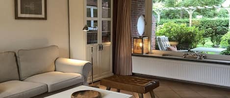 A living room with a sofa, a coffee table, a side table, a lamp, and a view of the outdoors through a window.