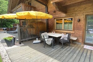 A wooden deck with a table and chairs, a yellow umbrella, and a wooden fence.