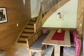 A wooden staircase leading to a room with a bench, a table, and patterned chairs.