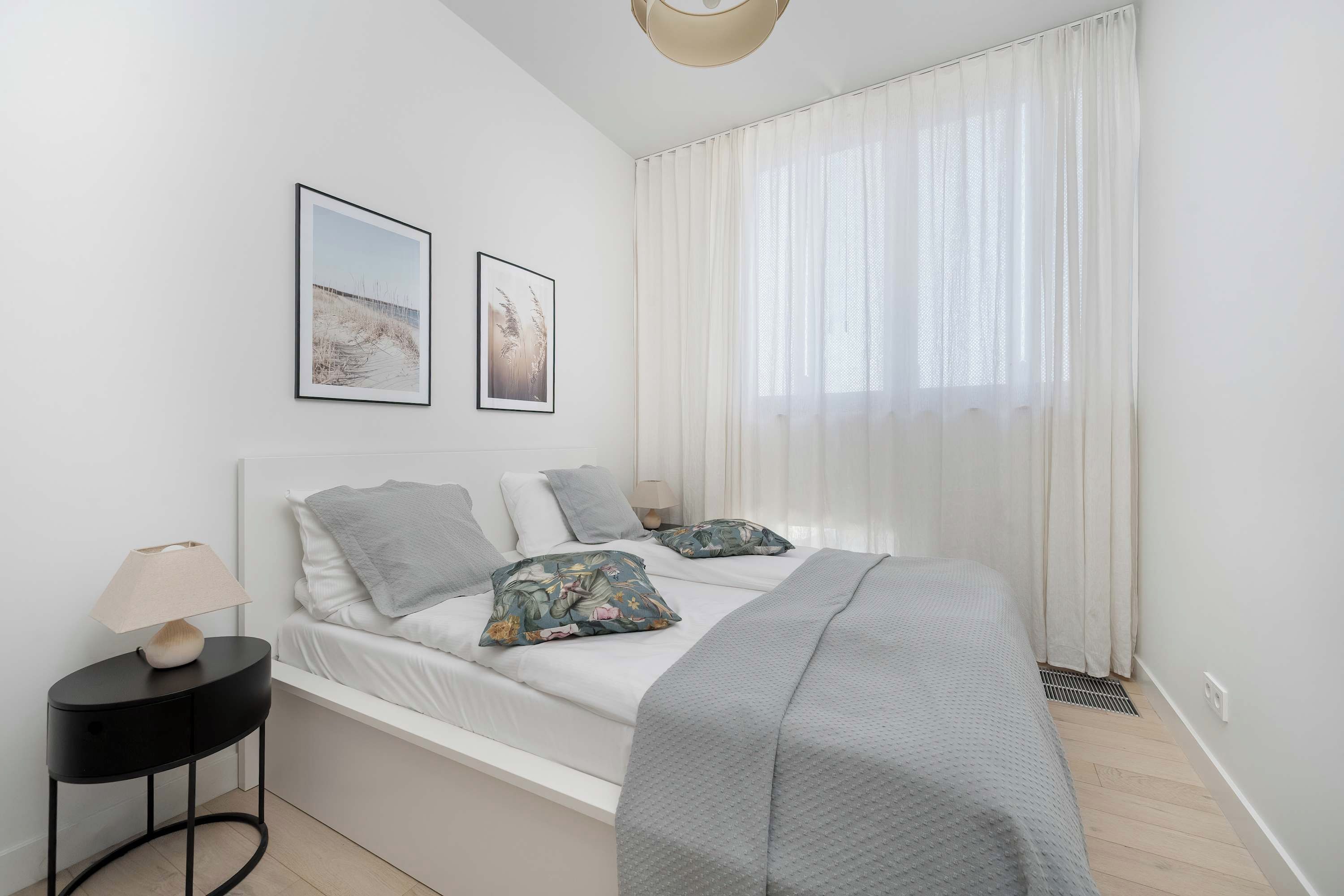 Ein Schlafzimmer mit einem Bett, einem Nachttisch, einer Lampe und zwei gerahmten Bildern an der Wand.