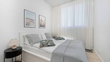 Ein Schlafzimmer mit einem Bett, einem Nachttisch, einer Lampe und zwei gerahmten Bildern an der Wand.