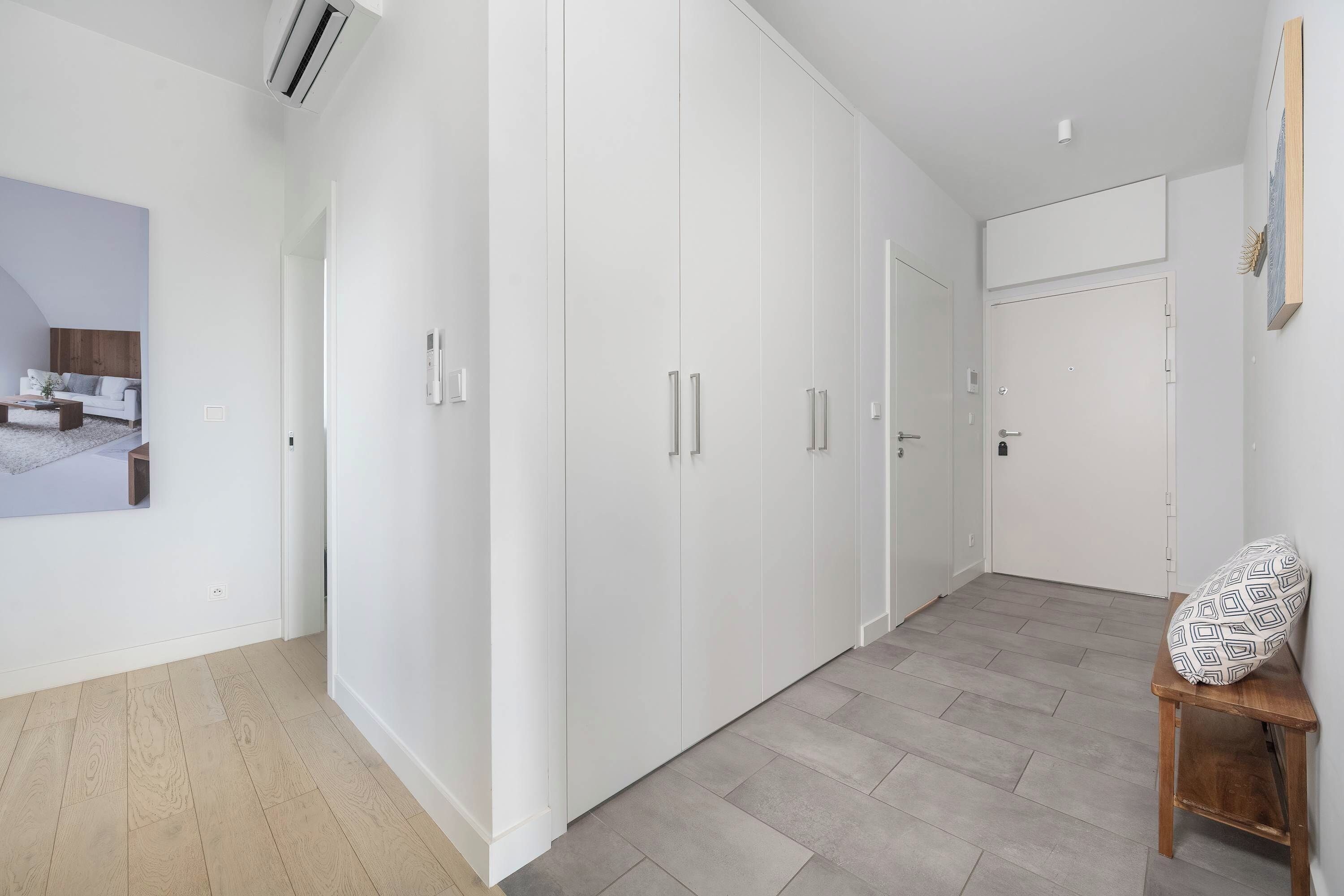 Un interior moderno con un armario, una cama y vistas a otra habitación con cama y ventana.