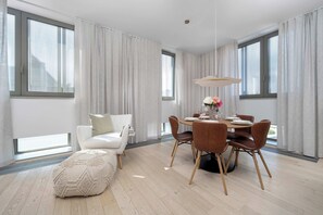 Ein moderner Essbereich mit einem runden Tisch, Ledersesseln und einem weißen Sofa.