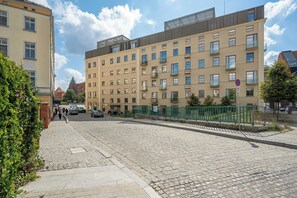 Ein mehrstöckiges Gebäude mit Ziegel Fassade, zahlreichen Fenstern und einem grünen Metallzaun.