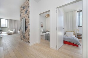 Ein modernes Schlafzimmer mit einem großen Spiegel, einem Bett mit rotem Gestell und Blick auf eine Stadtlandschaft durch das Fenster.