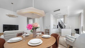 Uma sala de jantar moderna com mesa redonda de madeira, pratos brancos e copos de vidro transparente.