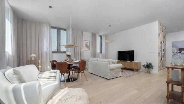 Uma sala de estar moderna com sofá, mesa de jantar, cadeiras, televisão e piso de madeira.