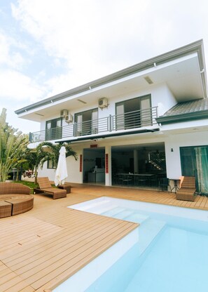 A modern two-story building with a swimming pool, outdoor seating, and a covered patio area. - Bohol Cattleya Resort (Panglao)