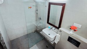 A modern bathroom with a glass shower enclosure, a white sink, and a mirror above it. - Revaas Lake View Boutique Hotel (Udaipur)