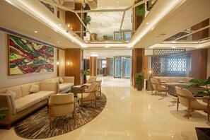 A spacious lobby with a high ceiling, a large abstract painting, and multiple seating areas. - Arista By Ambition - Guwahati (Guwahati)