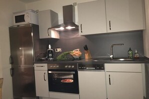 Cozinha compacta com forno embutido, micro-ondas e pia.