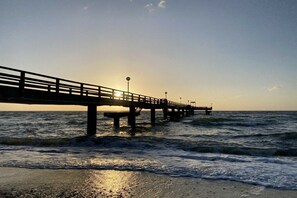 Een steiger die het water in reikt, met een zonsondergang op de achtergrond.