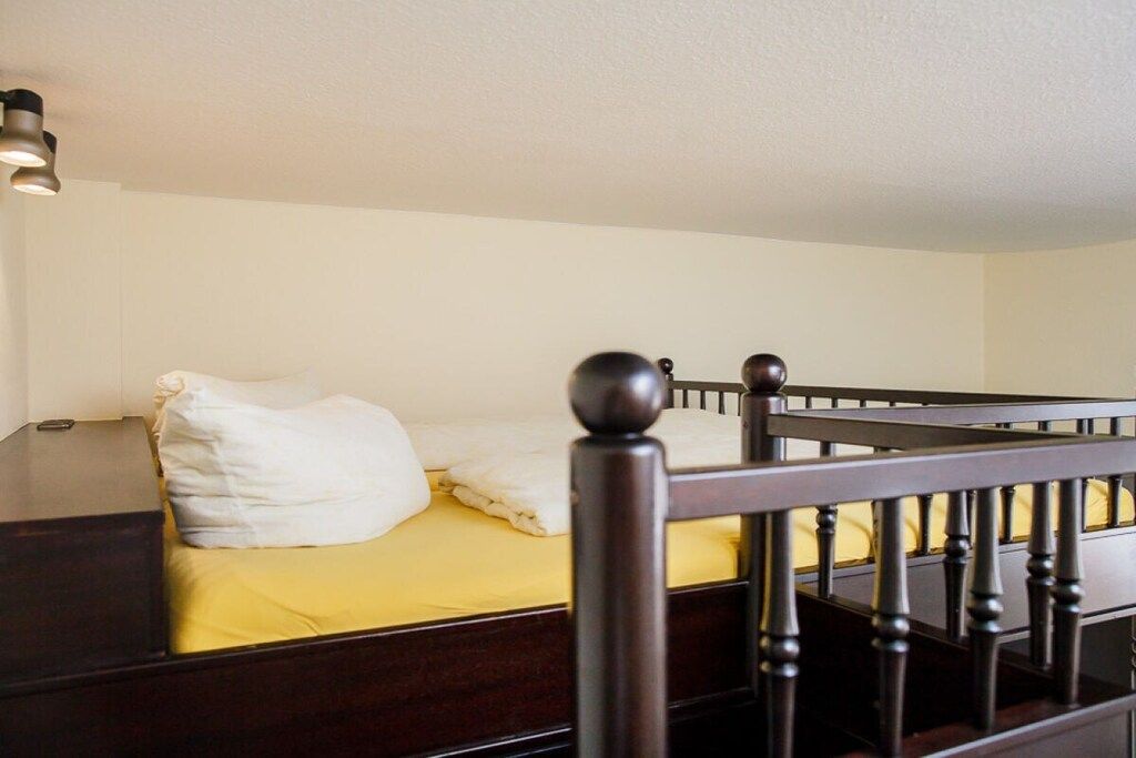 A single bed with a wooden headboard and a nightstand with a lamp.