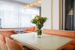 Ein modernes Zimmer mit Tisch, Blumen in einer Vase und einem Fenster mit Vorhängen.