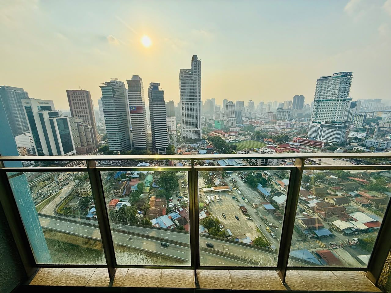 Vista de un paisaje urbano desde un balcón, con edificios modernos y una autopista al frente.